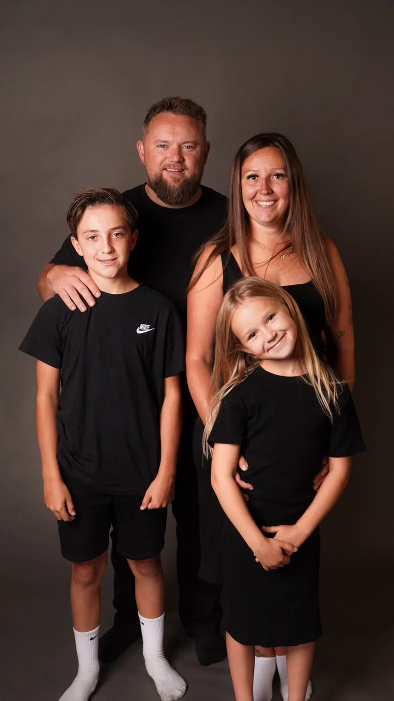A family of four photographed together on a studio backdrop
