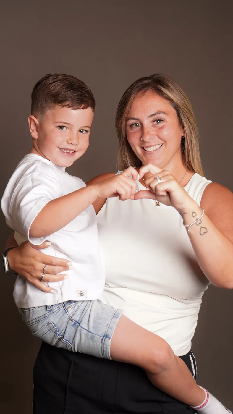 A mum and her son making a heart shape with their hands